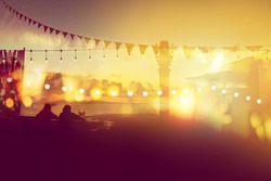 two friends watching sunset at restaurant on the beach, blurred bokeh light on sunset with yellow string lights decor in beach restaurant 