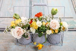 Floral arrangement with springtime flowers: roses, poppies and chamelaucium (wax flower).