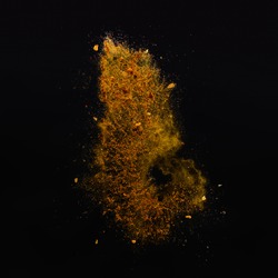 Orange spices powder explosion, flying pepper on black background. Freeze motion photo