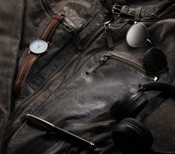 Men's accessories on leather jacket as background with blank space. Concept for the design 