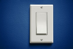 White light switch against blue wall