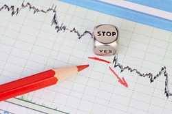 Downtrend financial market chart , red pencil, red arrow and dices cube with the word STOP. Selective focus