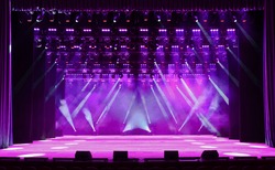 Illuminated empty magenta concert stage with fog and rays of light