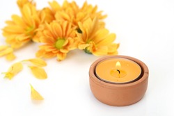 yellow flowers and burning candles on white background