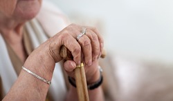 Old wrinkled woman hands holding walking stick