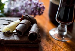 Chocolate dessert with port wine, dark chocolate curls, white chocolate curl,  chocolate fudge sauce on cocoa cookie on wood with fresh lilac spring flowers romantic gourmet Photography 