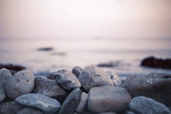 Pebble stones on the shore close up in the blurry sunset light