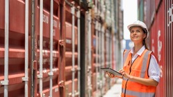 Female container yard manager using tablet working at container yard. Container yard warehouse, Cargo Shipping Import and Export industry. Logistic shipping yard business.