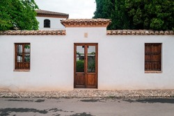 A rustic door in a latin village architecture style, that could be from Europe or America, surrounded by a road, garden wall and trees. Backdrop for graphic resource or decorative copy space.