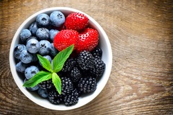 Various berries in a white bowl, top view
