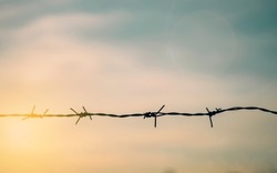 Barrier wire fence with sunset Twilight sky. Chain spike for world war safe security boundary concept for human rights slave, prison hostage hope to peace. International liberty day. russia ukraine