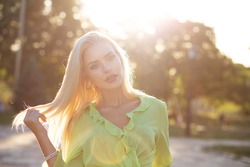 Closeup street portrait of a luxurious elegant woman with long hair walking at sunset. Space for text