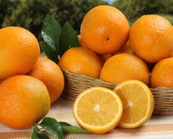 Some oranges in a basket over a wooden surface on a orange field as background