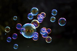 Rainbow soap bubbles on a dark background.