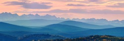 Wide angle panorama autumn forest,misty hills mountain tops in pink dawn