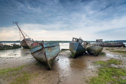 Abandoned fishing boats under a brooding sky at Pin Mill on the River Orwell near Ipswich on the Suffolk coast