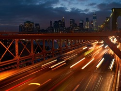 Long exposure shot of cars leaving Manhattan via Brooklyn Bridge in New York at dusk