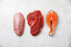 Raw food turkey breast, beef meat and Salmon oily fish steak on white textured background