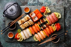 Sushi Set nigiri and sushi rolls with tea served on gray stone slate on metal background