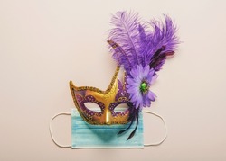 Concept of carnival during covid-19. Venetian carnival mask with protective surgical mask over light background. Carnival celebration concept