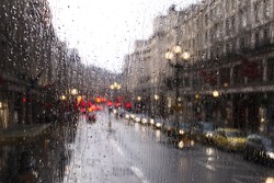 blurred view of road traffic in London on a rainy day through the bus window. raindrops on the glass window of the bus.