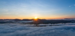 The sun rises above the high mountain peaks. and morning fog at Pha Chanadai National Park during the new year 2022