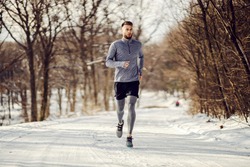 Fit sportsman running in nature on snow at winter. Healthy lifestyle, winter fitness, cold weather