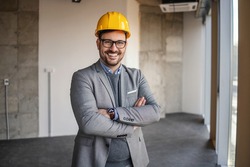 Businessman standing in building in construction process with arms crossed and looking at camera.