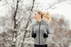 Happy sportswoman jogging in forest at snowy winter day. Winter sport, healthy habits