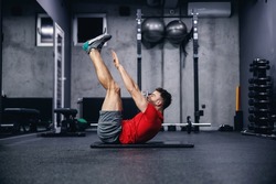 Fitness routine and weight loss, sports life. Man correctly performs demanding core exercises on the pathos of the modern gym and sports center concept. Individual training and achieving fitness goals