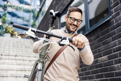 A smiling urban man going down the stairs outside with bike on his shoulder.