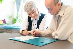 Asian senior couple filling out paperwork.
