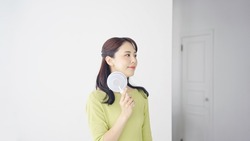 Young Asian woman using a portable fan.