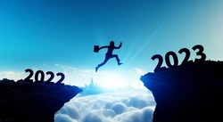 New year concept of 2023. New year's card. Silhouette of a man jumping over a cliff.
