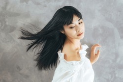 Fashion portrait of young Asian attractive woman blowing her long black hair. Hair care concept. cosmetics. Beauty salon.