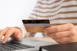 Woman with credit card and laptop at table, closeup. Internet shopping concept