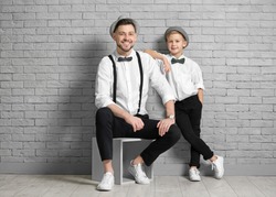 Father and son in elegant suits against brick wall