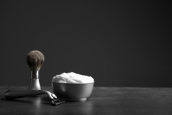 Barber brush, shaving foam and razor for man on table against dark background