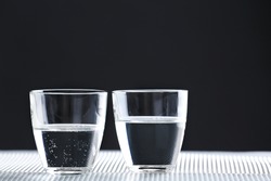 Two glasses of water on table on dark background