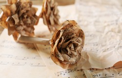 Beautiful paper-made roses on musical notes page background