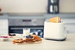 Toaster with dishes and sandwiches on a light kitchen table