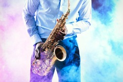 African American jazz musician playing the saxophone against colorful smoky background