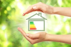 Female hands and house with energy efficiency scale image on natural background