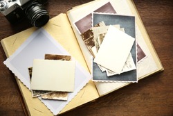 Album with vintage photos and camera on wooden background