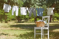 Wicker basket on white chair and baby laundry hanging on clothesline