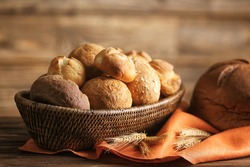 Bread and lots of fresh bread buns in a basket on a wooden table