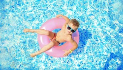 Little boy with pink rubber ring in swimming pool