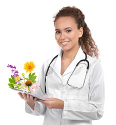 Young female doctor with tablet and flowers bouquet on white background. Alternative medicine concept.