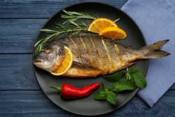 Tasty fish with vegetables and lemon on kitchen table