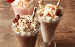 Delicious milkshakes on wooden background